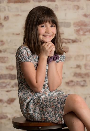 smiling girl sitting on a stool